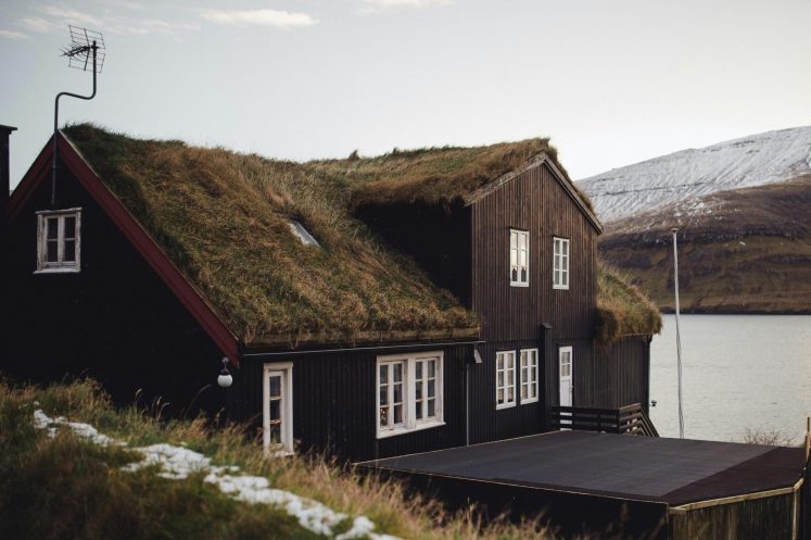 Charming turf-roofed house in Bøur, Faroe Islands, capturing rustic architecture against a serene landscape.