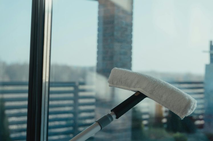 A modern cleaning tool used to clean a large glass window with a clear outdoor view.